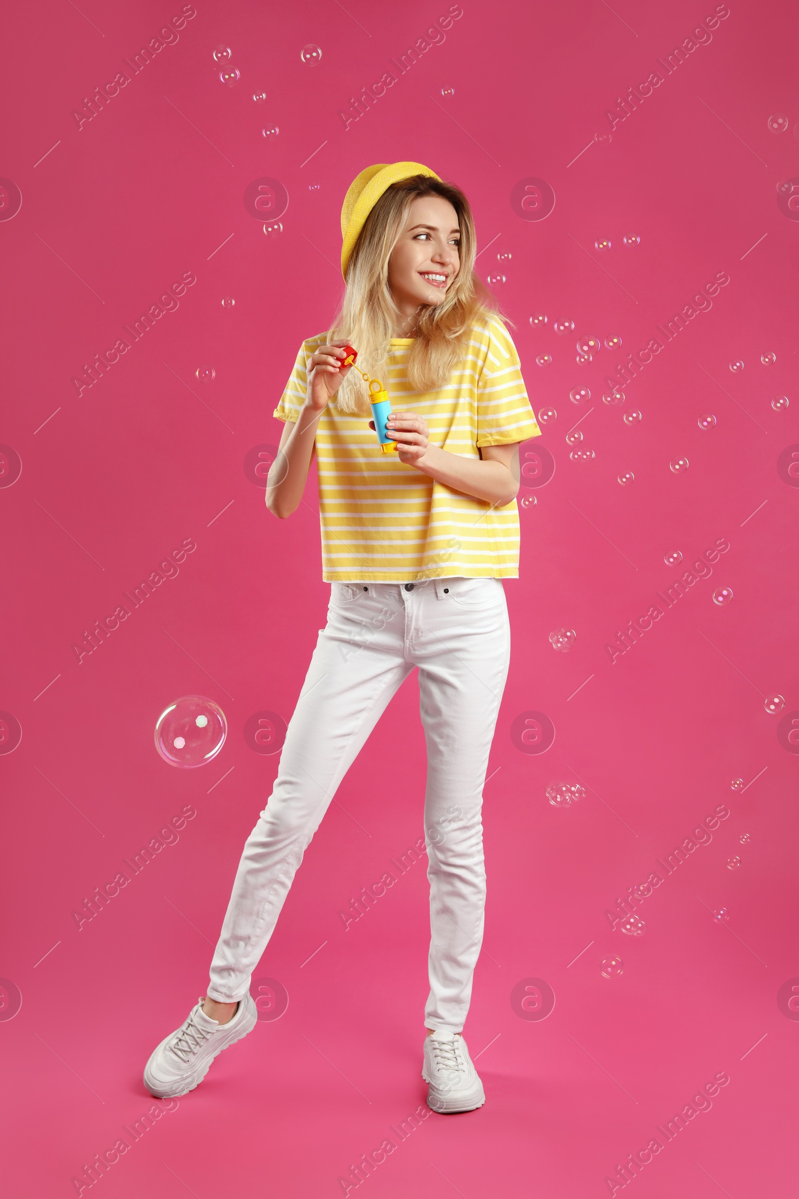 Young woman blowing soap bubbles on pink background Photo of Young woman blowing soap bubbles on pink background