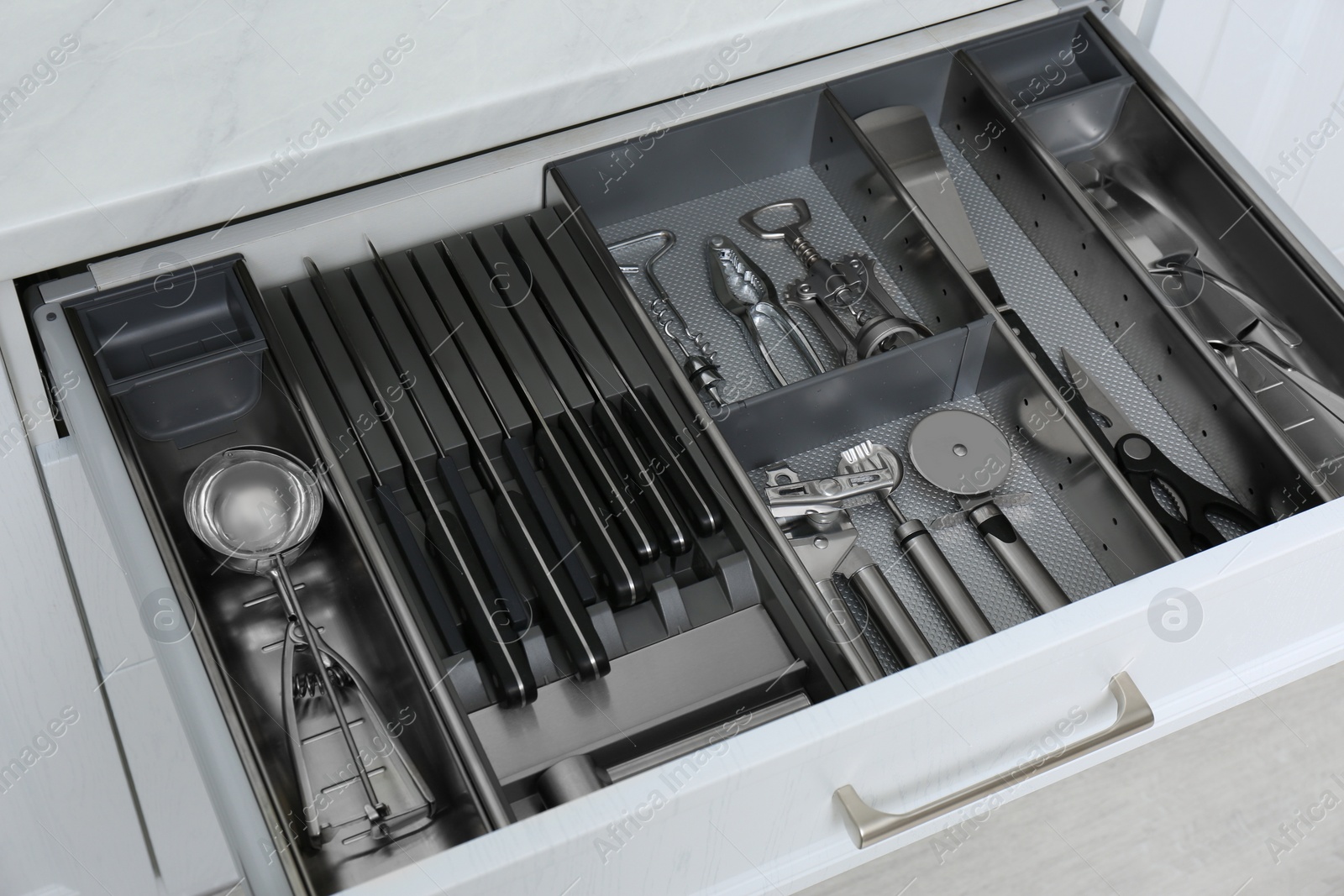 Open drawer with stainless steel utensil set, closeup. Order in kitchen Photo of Open drawer with stainless steel utensil set, closeup. Order in kitchen