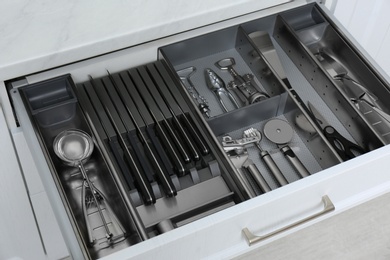 Open drawer with stainless steel utensil set, closeup. Order in kitchen Photo of Open drawer with stainless steel utensil set, closeup. Order in kitchen