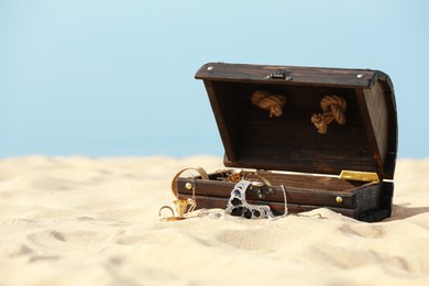Open wooden chest with treasures on sandy beach, space for text Photo of Open wooden chest with treasures on sandy beach, space for text