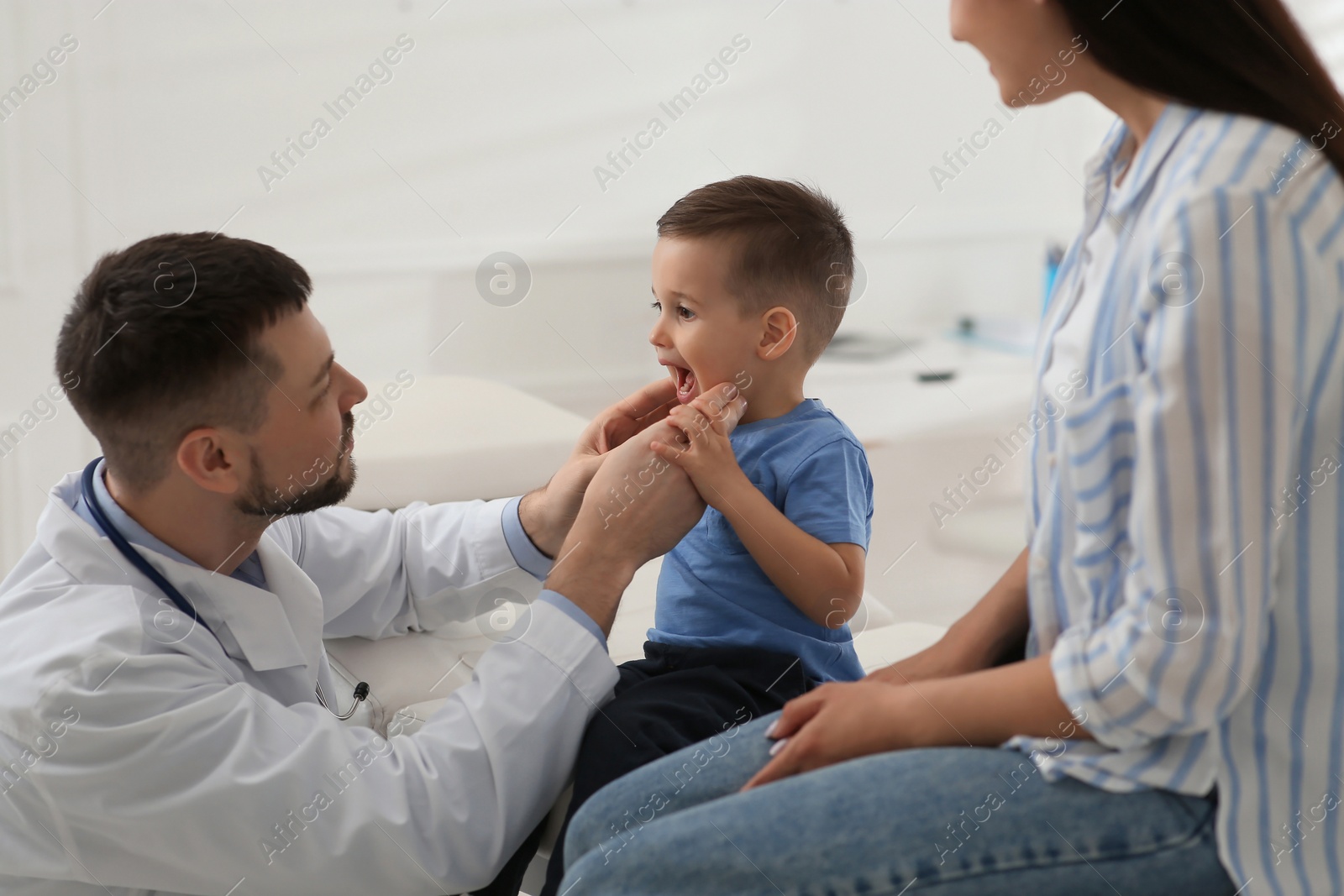 Mother and son visiting pediatrician in hospital. Doctor examining little boy Photo of Mother and son visiting pediatrician in hospital. Doctor examining little boy