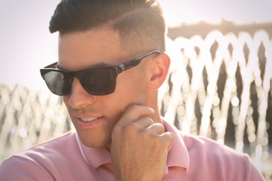 Handsome man wearing stylish sunglasses on city street, closeup Photo of Handsome man wearing stylish sunglasses on city street, closeup