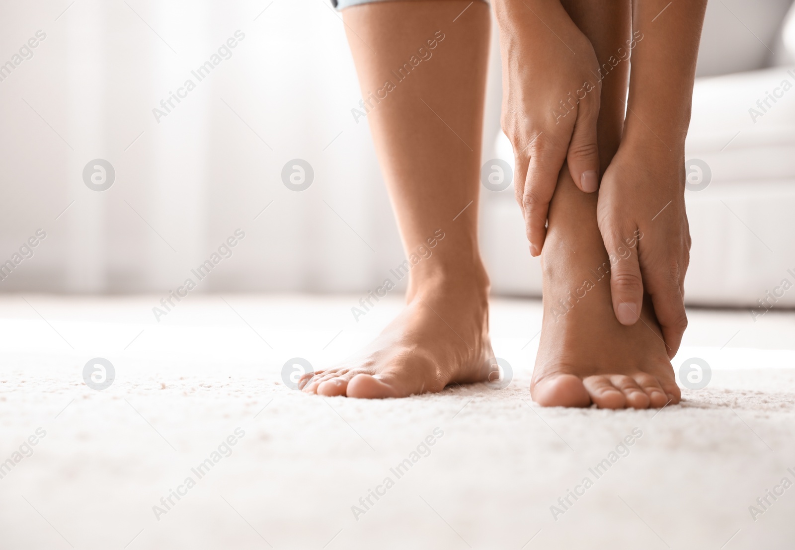 Young woman suffering from pain in foot indoors, closeup Photo of Young woman suffering from pain in foot indoors, closeup