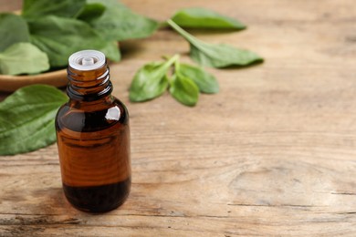 Bottle of broadleaf plantain extract and leaves on wooden table, space for text Photo of Bottle of broadleaf plantain extract and leaves on wooden table, space for text