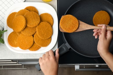 Woman cooking breaded cutlets in frying pan on stove, top view Photo of Woman cooking breaded cutlets in frying pan on stove, top view