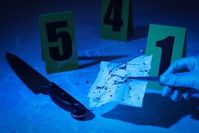 Closeup view of woman taking bloody napkin at marble background, toned in blue. Crime scene Photo of Closeup view of woman taking bloody napkin at marble background, toned in blue. Crime scene