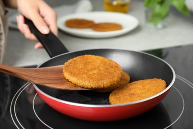 Woman cooking breaded cutlets in frying pan on stove, closeup Photo of Woman cooking breaded cutlets in frying pan on stove, closeup