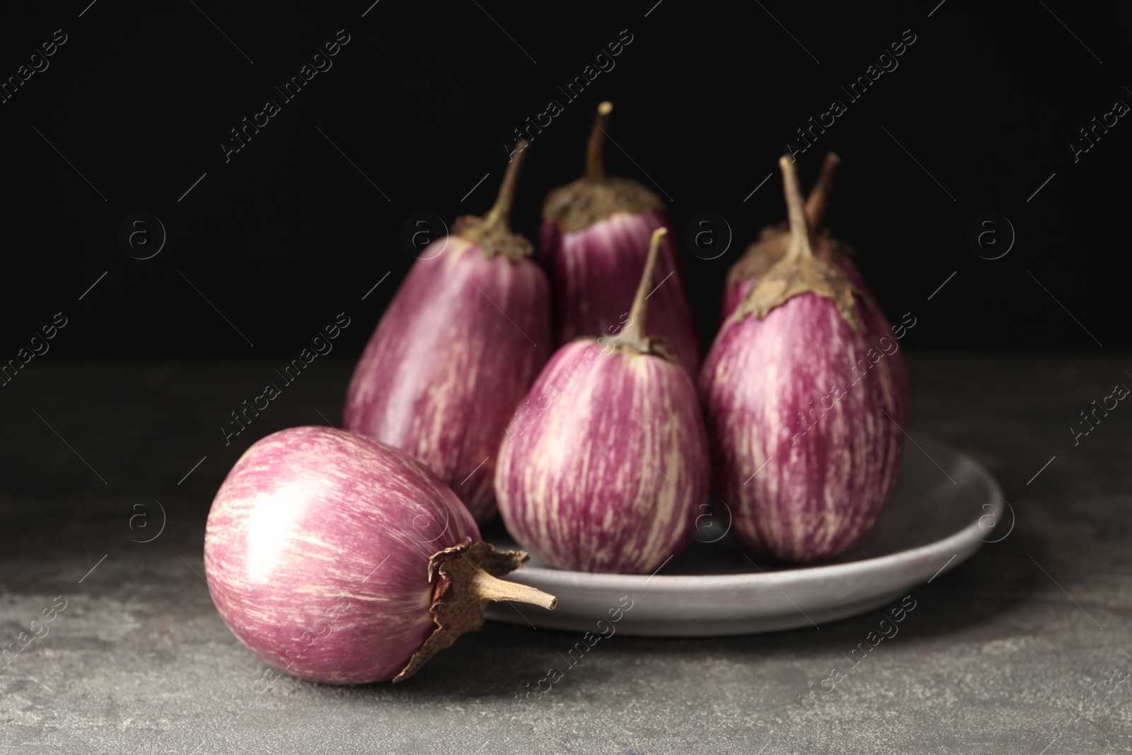Ripe purple eggplants on grey table, closeup Photo of Ripe purple eggplants on grey table, closeup