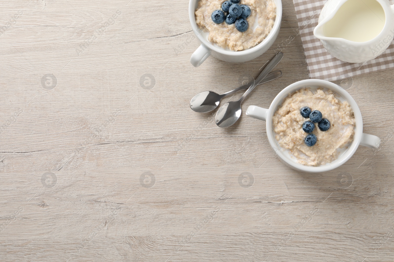 Tasty oatmeal porridge with blueberries served on light wooden table, flat lay. Space for text Photo of Tasty oatmeal porridge with blueberries served on light wooden table, flat lay. Space for text