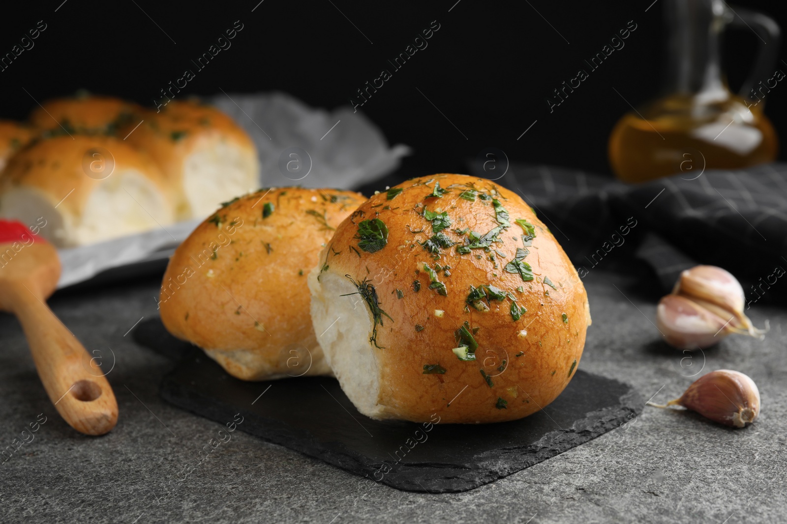 Traditional pampushka buns with garlic and herbs on grey table, closeup Photo of Traditional pampushka buns with garlic and herbs on grey table, closeup