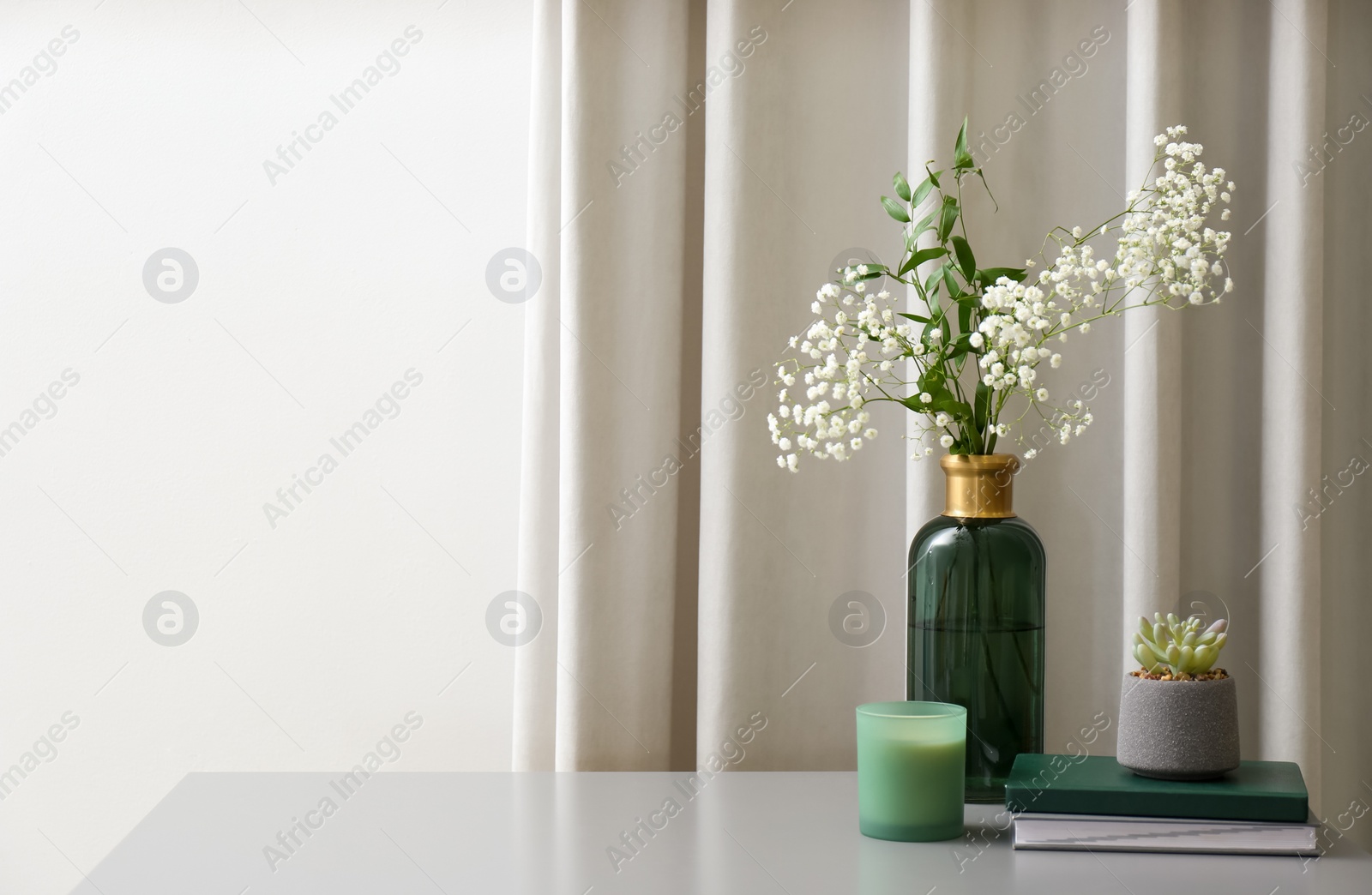 Vase with beautiful flowers, candle and books on grey table indoors, space for text. Interior elements Photo of Vase with beautiful flowers, candle and books on grey table indoors, space for text. Interior elements
