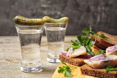 Photo of Cold Russian vodka with snacks on wooden table, closeup