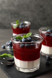 Delicious panna cotta with fruit coulis and fresh blueberries served on grey table Photo of Delicious panna cotta with fruit coulis and fresh blueberries served on grey table