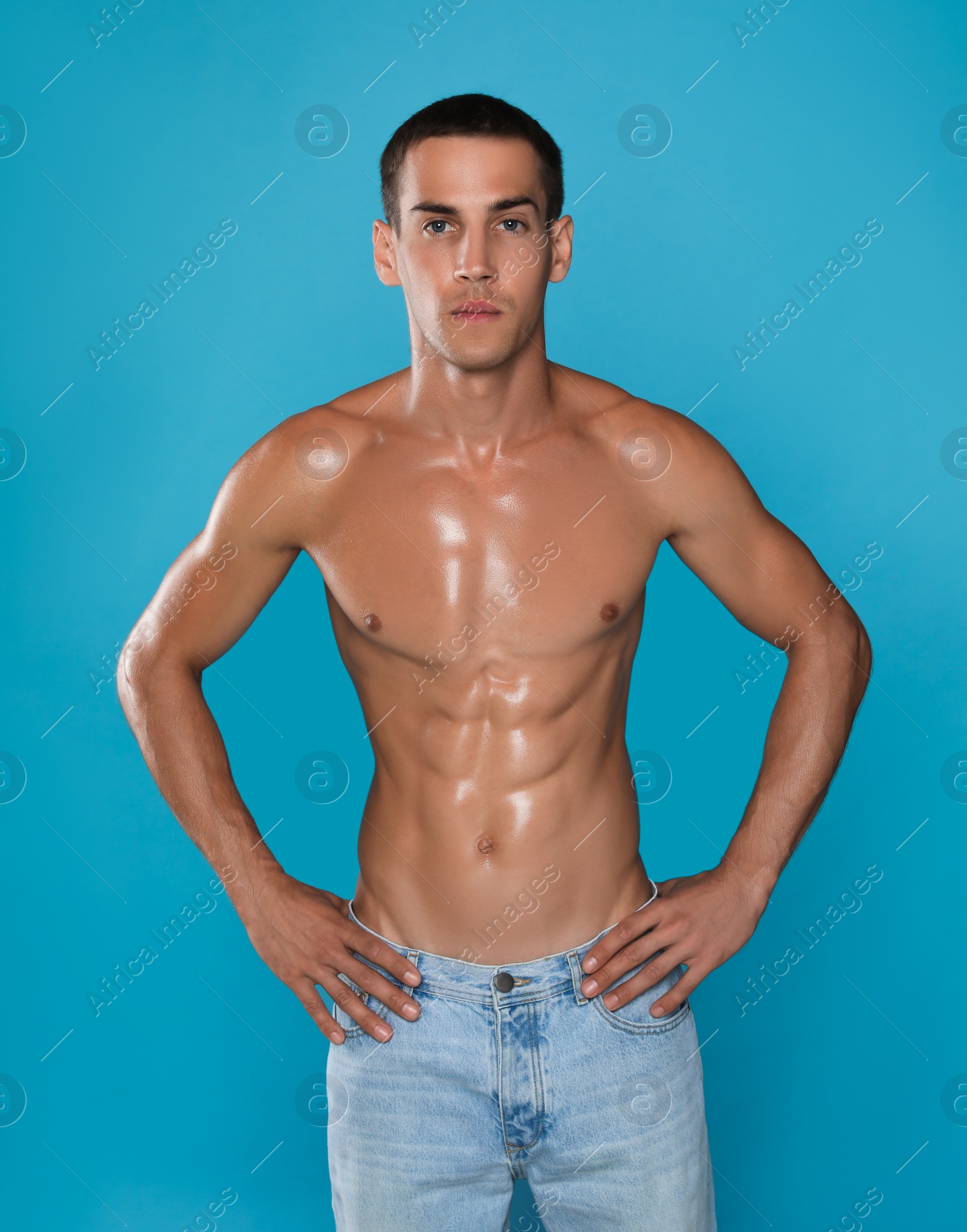 Handsome shirtless man with slim body on light blue background Photo of Handsome shirtless man with slim body on light blue background