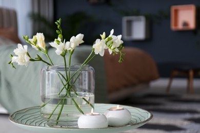 Vase with beautiful freesia flowers and burning candles on stand in bedroom, space for text. Interior elements Photo of Vase with beautiful freesia flowers and burning candles on stand in bedroom, space for text. Interior elements