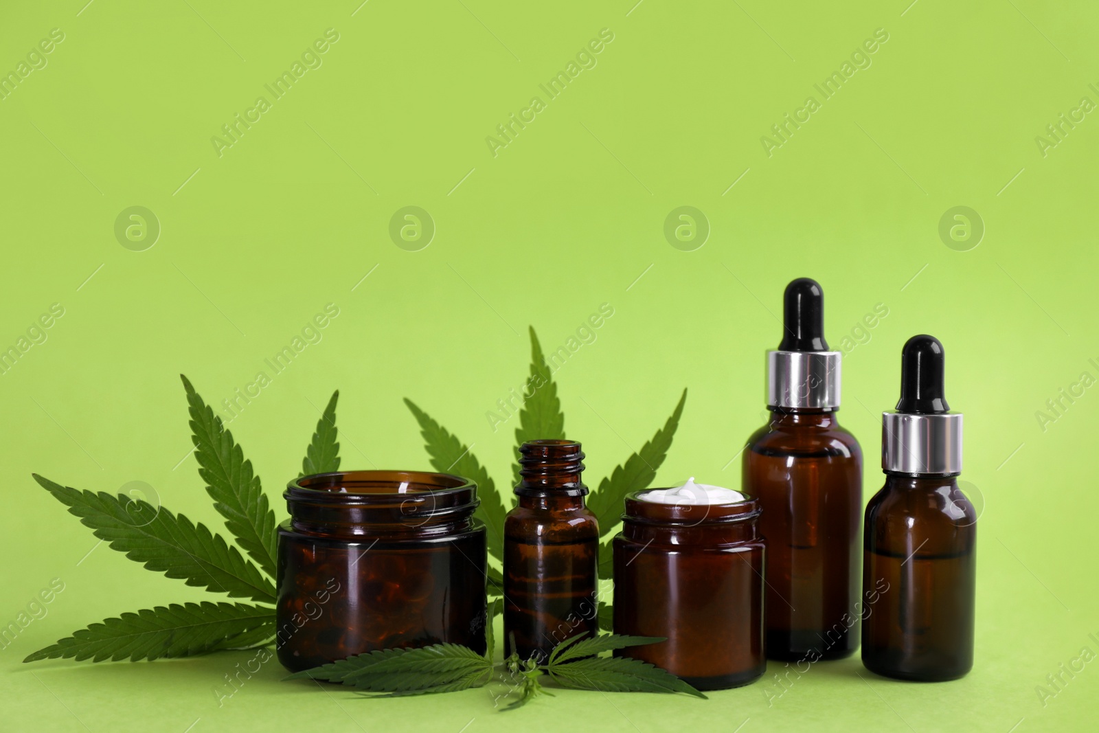 Composition with CBD oil, THC tincture and hemp leaves on light green background Photo of Composition with CBD oil, THC tincture and hemp leaves on light green background