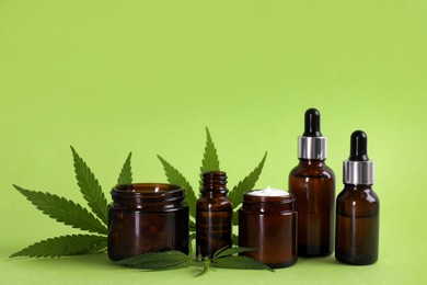 Composition with CBD oil, THC tincture and hemp leaves on light green background Photo of Composition with CBD oil, THC tincture and hemp leaves on light green background