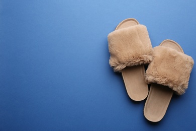 Pair of soft slippers on blue background, flat lay. Space for text Photo of Pair of soft slippers on blue background, flat lay. Space for text