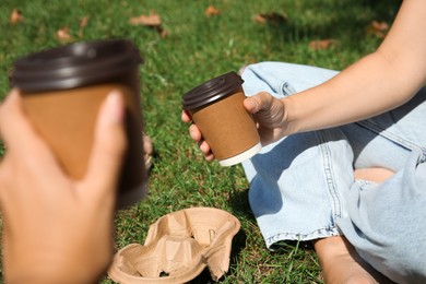 Women holding takeaway cardboard coffee cups with plastic lids outdoors, closeup Photo of Women holding takeaway cardboard coffee cups with plastic lids outdoors, closeup
