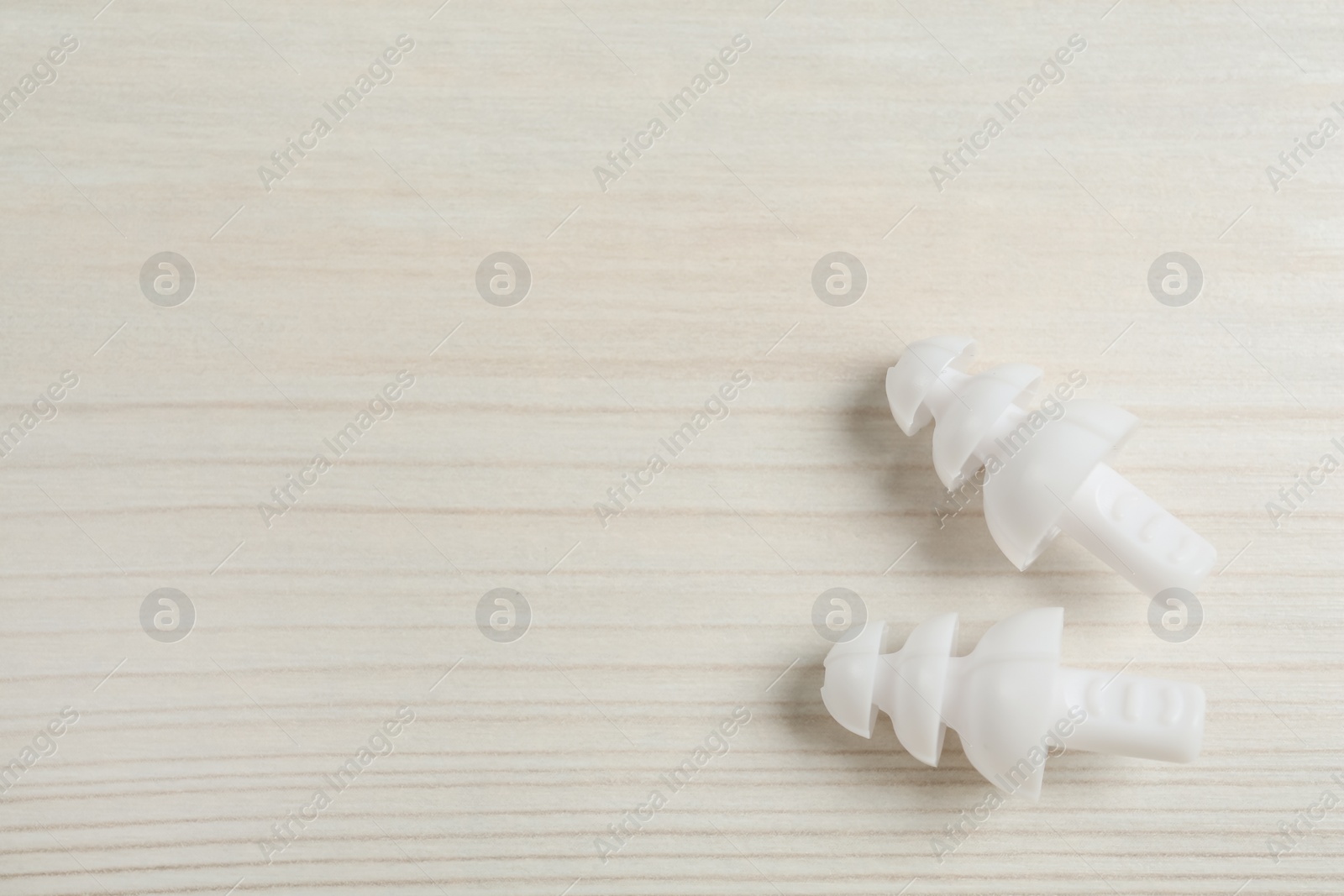 Pair of ear plugs on white wooden background, flat lay. Space for text Photo of Pair of ear plugs on white wooden background, flat lay. Space for text