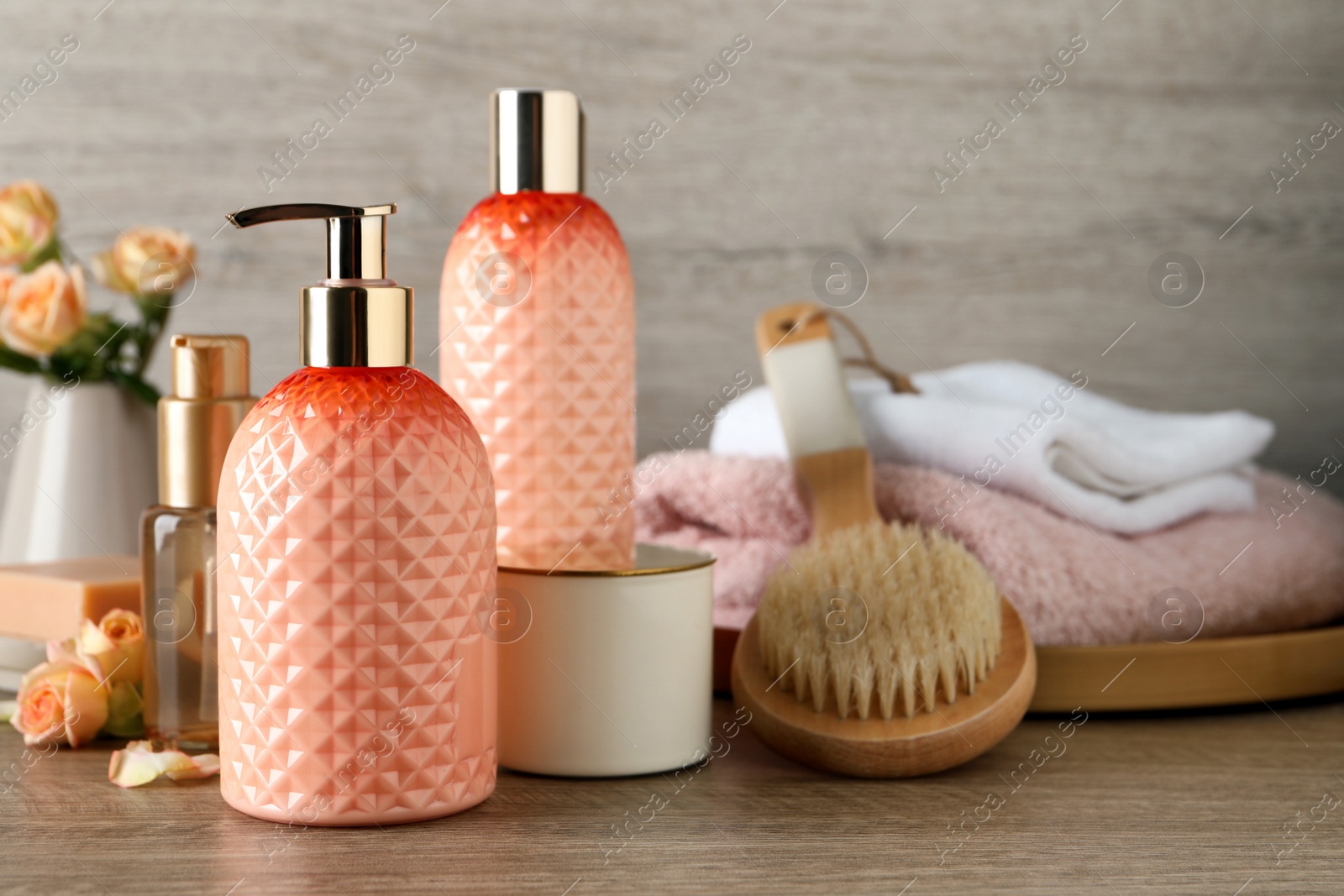 Stylish dispenser with liquid soap and other bathroom amenities on wooden table, space for text Photo of Stylish dispenser with liquid soap and other bathroom amenities on wooden table, space for text