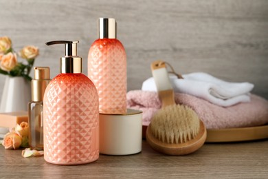 Photo of Stylish dispenser with liquid soap and other bathroom amenities on wooden table, space for text