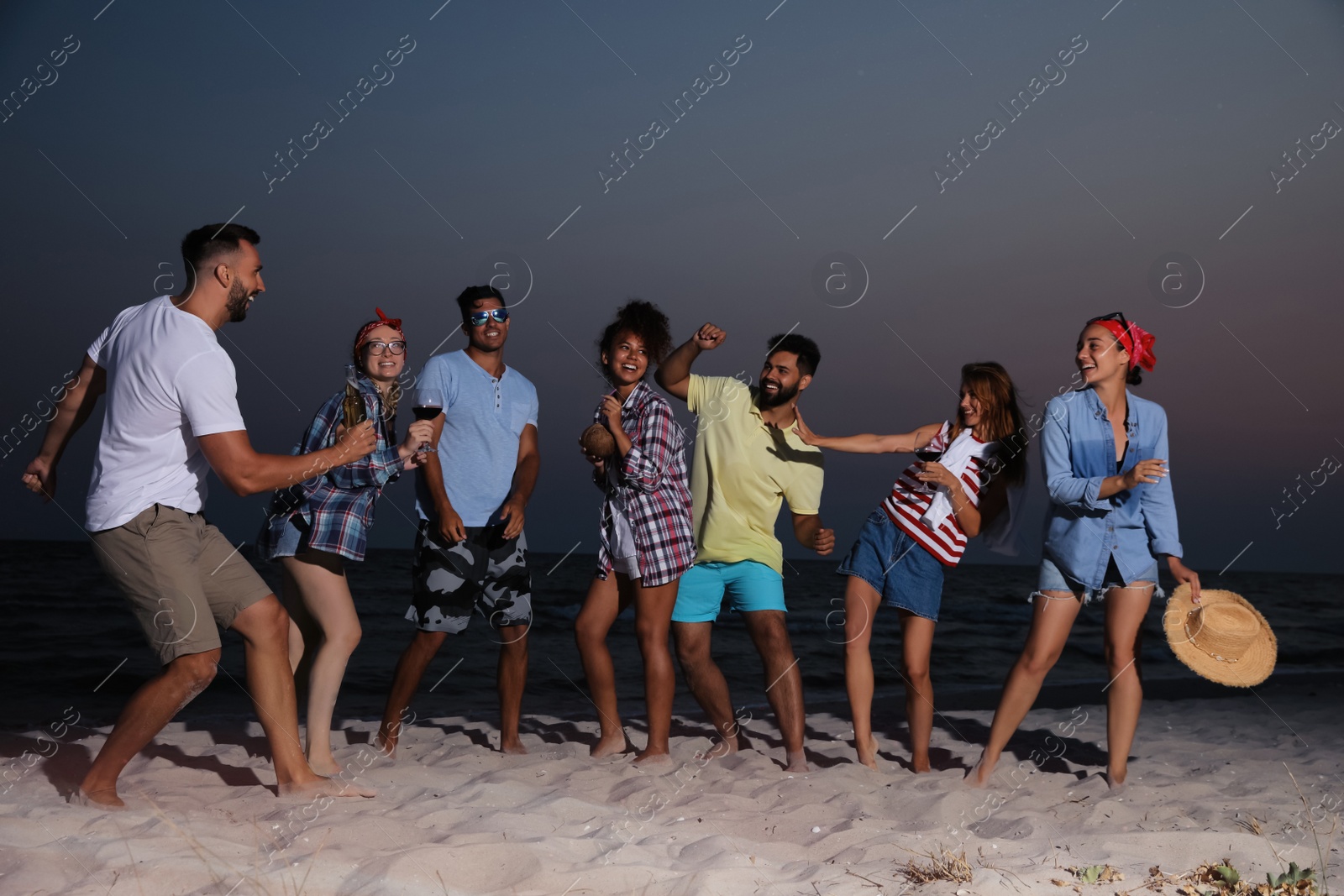 Happy friends enjoying summer beach party in evening Photo of Happy friends enjoying summer beach party in evening