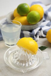 Glass squeezer with lemon and juice on light table Photo of Glass squeezer with lemon and juice on light table