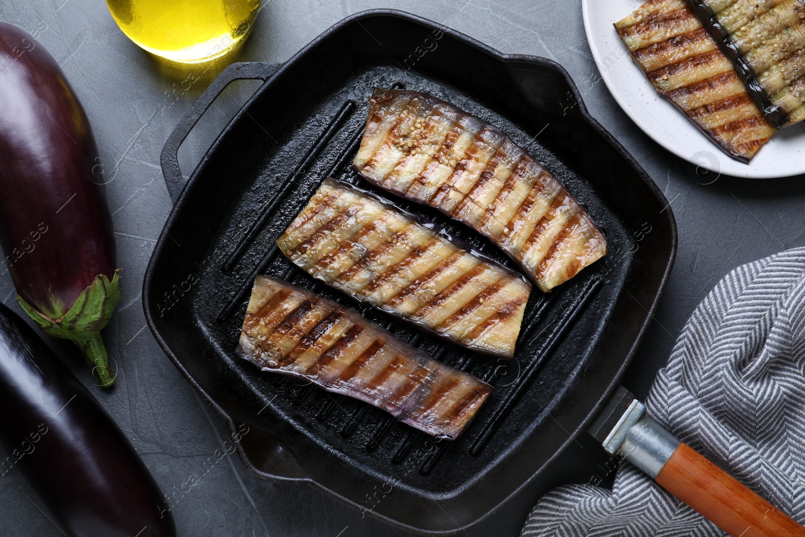Delicious grilled eggplant slices in pan on grey table, flat lay Photo of Delicious grilled eggplant slices in pan on grey table, flat lay