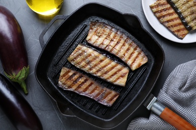 Photo of Delicious grilled eggplant slices in pan on grey table, flat lay