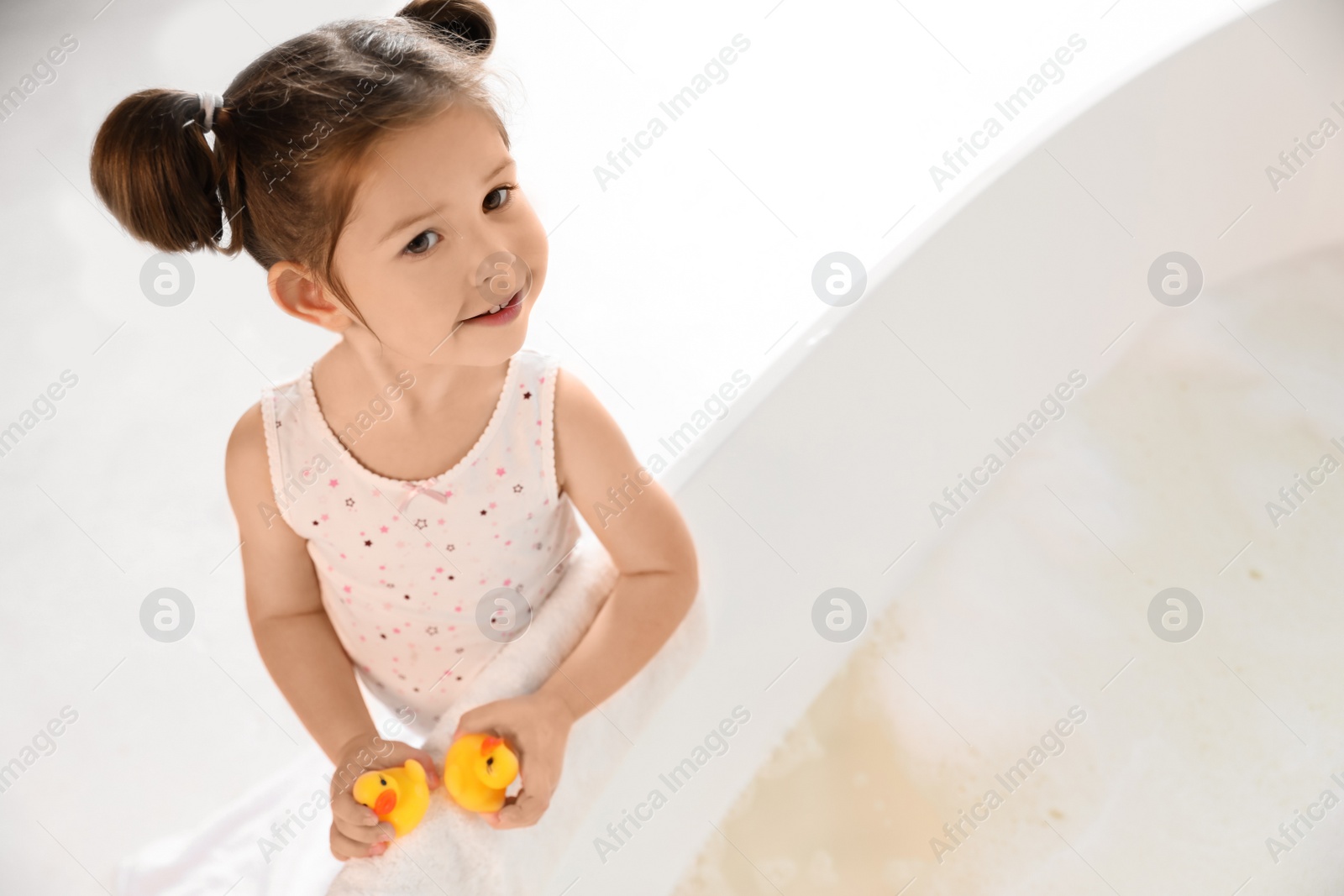 Cute little girl near tub in bathroom. Space for text Photo of Cute little girl near tub in bathroom. Space for text