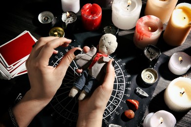 Woman stabbing voodoo doll with needle at table, closeup. Curse ceremony Photo of Woman stabbing voodoo doll with needle at table, closeup. Curse ceremony
