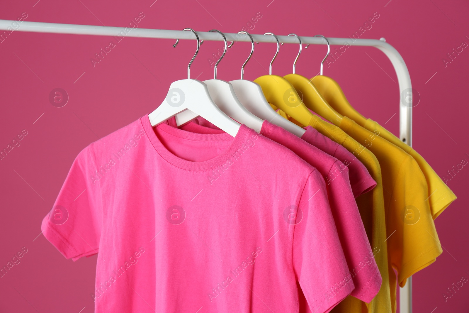 Photo of Rack with stylish children clothes on pink background, closeup