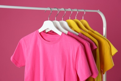 Rack with stylish children clothes on pink background, closeup Photo of Rack with stylish children clothes on pink background, closeup