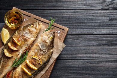 Tasty homemade roasted perches on black wooden table, top view and space for text. River fish Photo of Tasty homemade roasted perches on black wooden table, top view and space for text. River fish