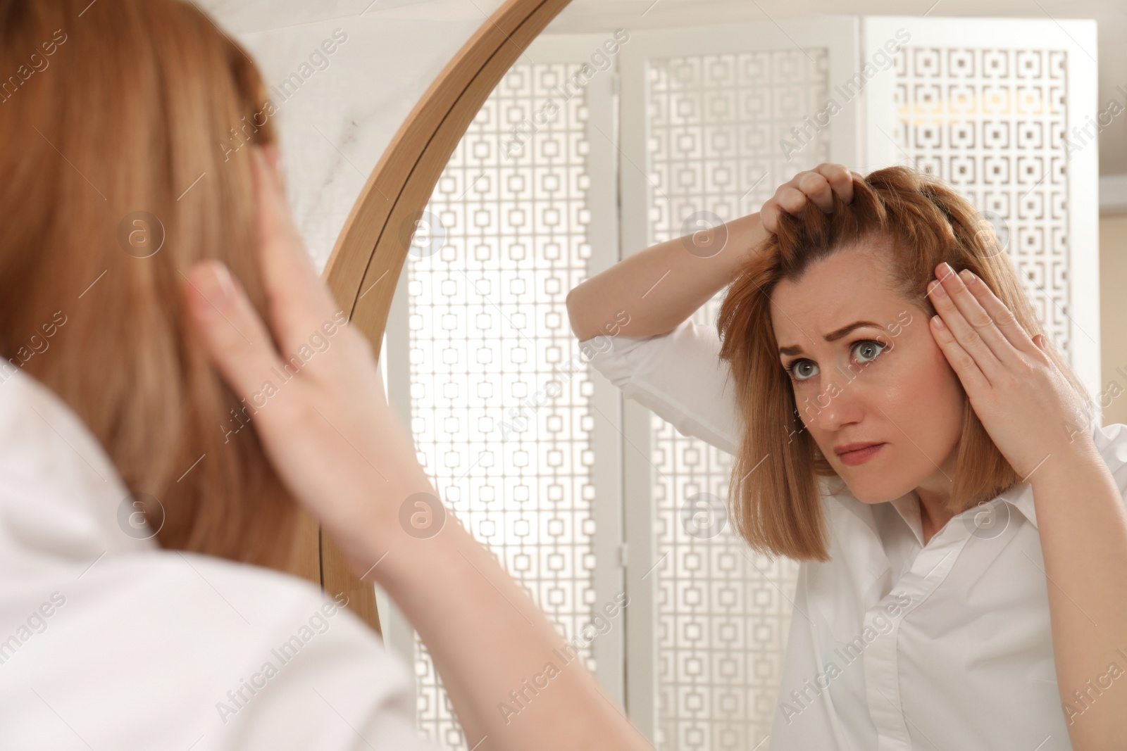 Emotional woman suffering from baldness near mirror at home Photo of Emotional woman suffering from baldness near mirror at home