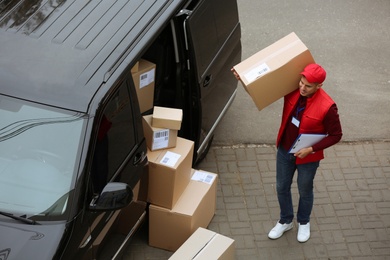 Courier with clipboard and parcel near delivery van outdoors, above view Photo of Courier with clipboard and parcel near delivery van outdoors, above view