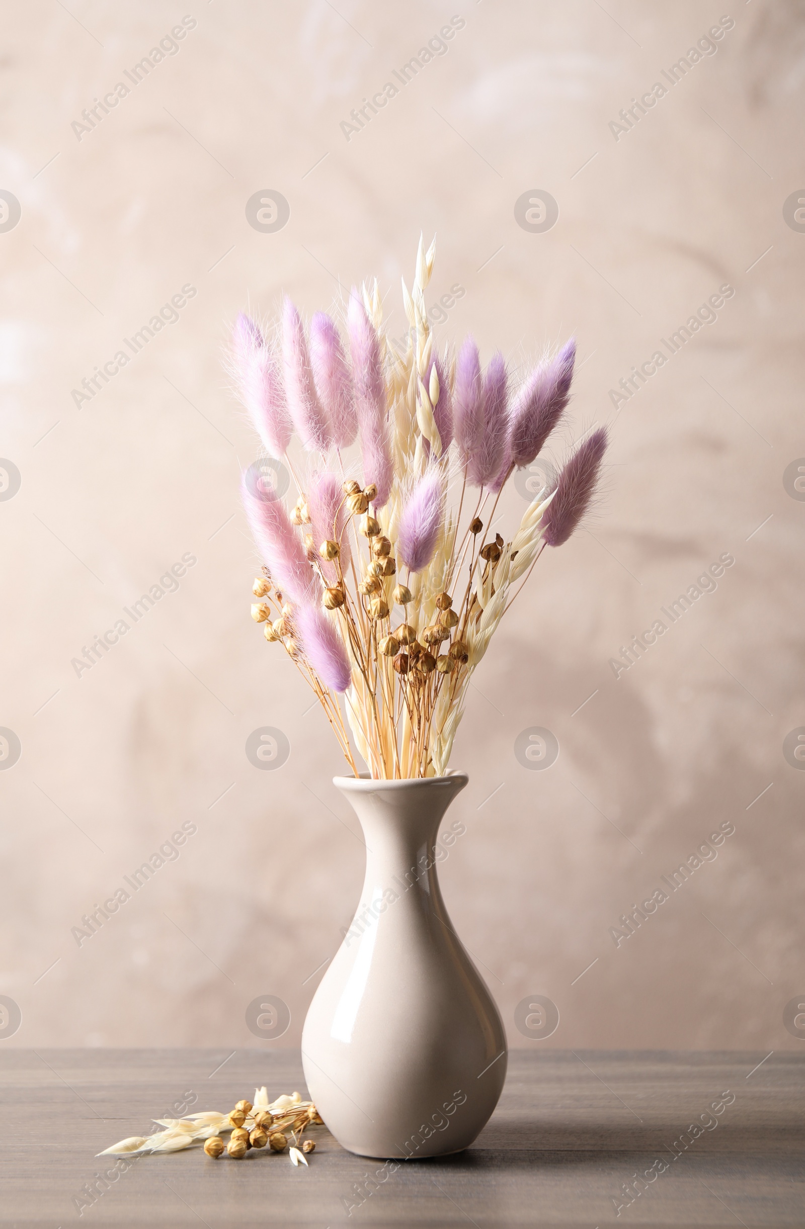 Dried flowers in vase on table against light grey background Photo of Dried flowers in vase on table against light grey background