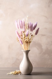 Dried flowers in vase on table against light grey background Photo of Dried flowers in vase on table against light grey background