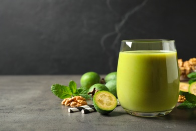 Fresh feijoa smoothie in glass on grey table, space for text Photo of Fresh feijoa smoothie in glass on grey table, space for text