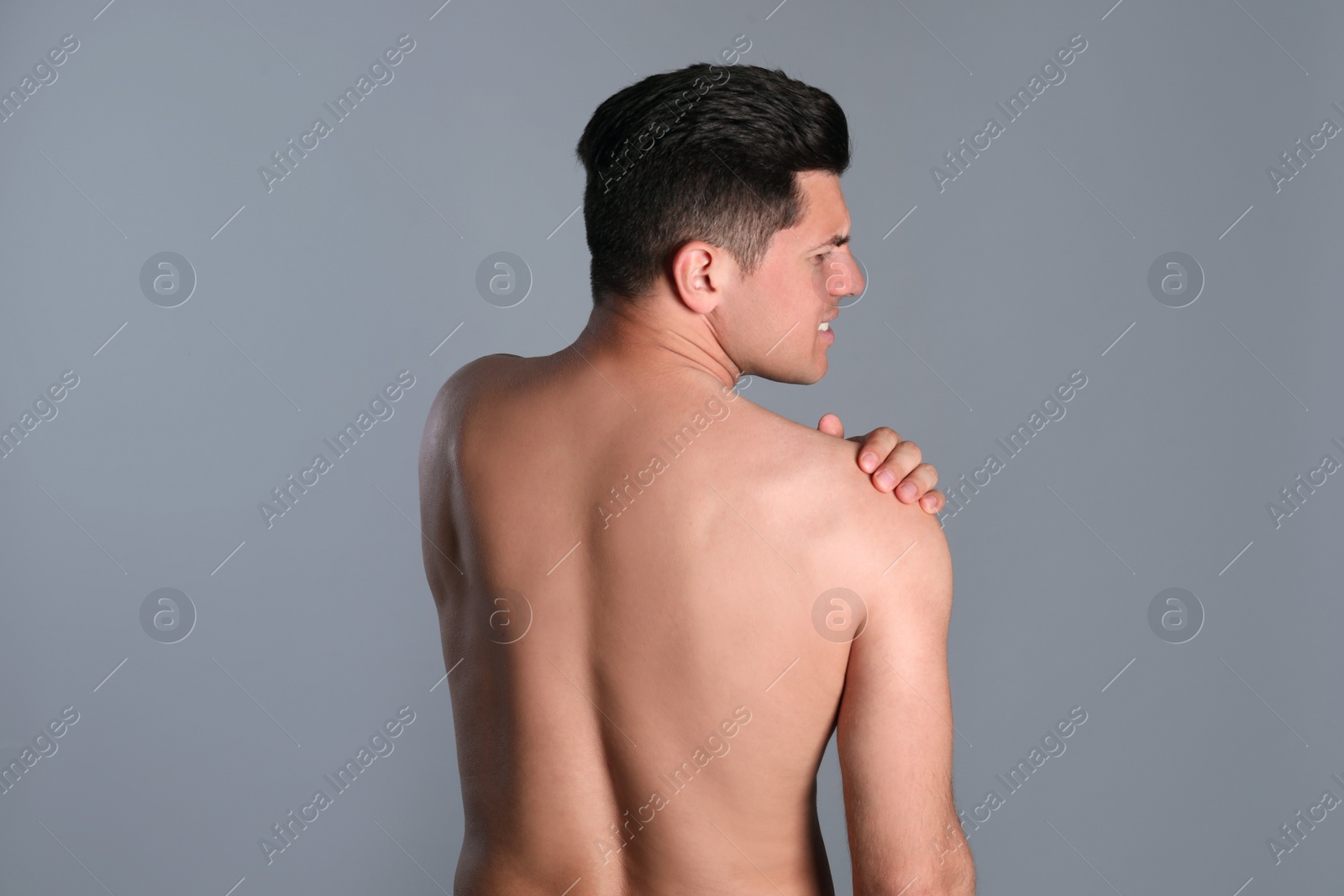 Photo of Man suffering from shoulder pain on grey background