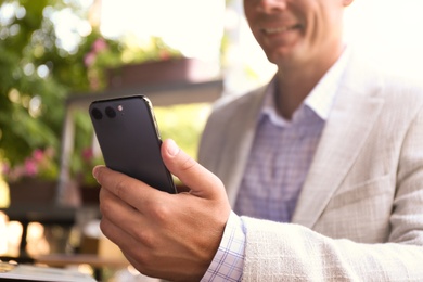 Businessman with smartphone in outdoor cafe, closeup Photo of Businessman with smartphone in outdoor cafe, closeup