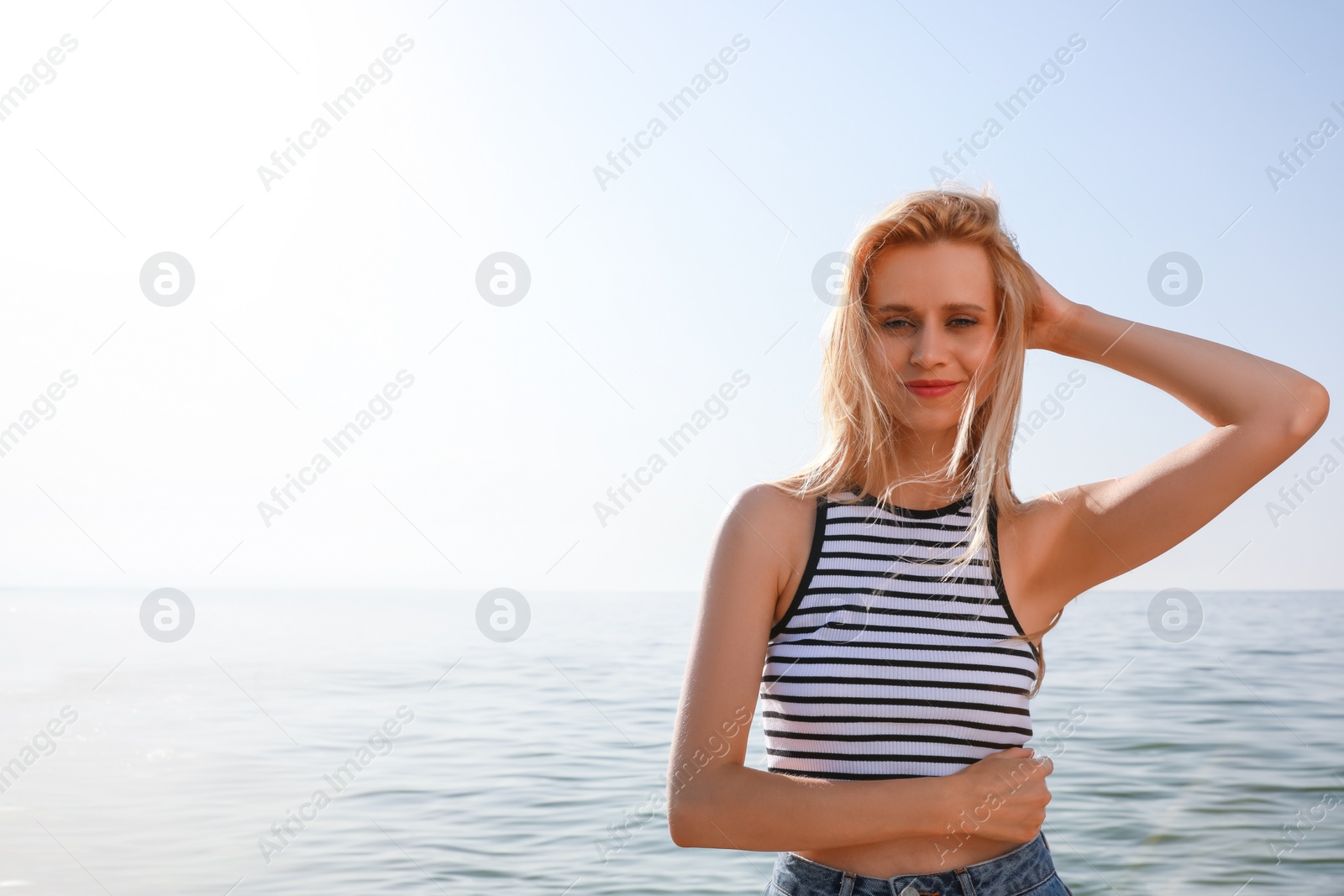 Beautiful young woman near sea on sunny day in summer, space for text Photo of Beautiful young woman near sea on sunny day in summer, space for text