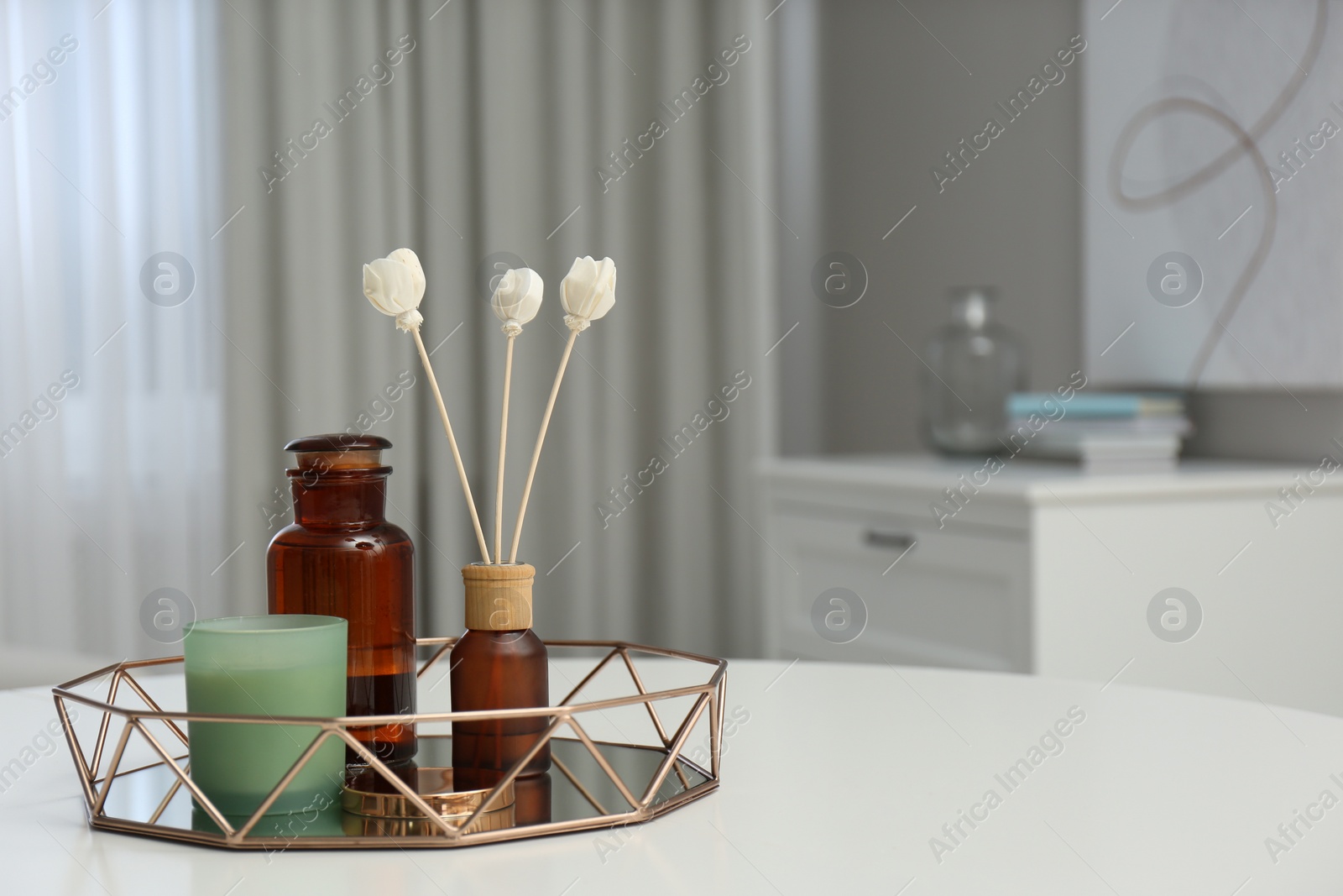 Air reed freshener and candle on white table in room, space for text Photo of Air reed freshener and candle on white table in room, space for text