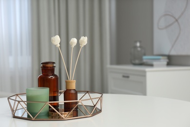 Air reed freshener and candle on white table in room, space for text Photo of Air reed freshener and candle on white table in room, space for text