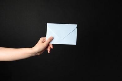 Woman holding white paper envelope on black background, closeup Photo of Woman holding white paper envelope on black background, closeup