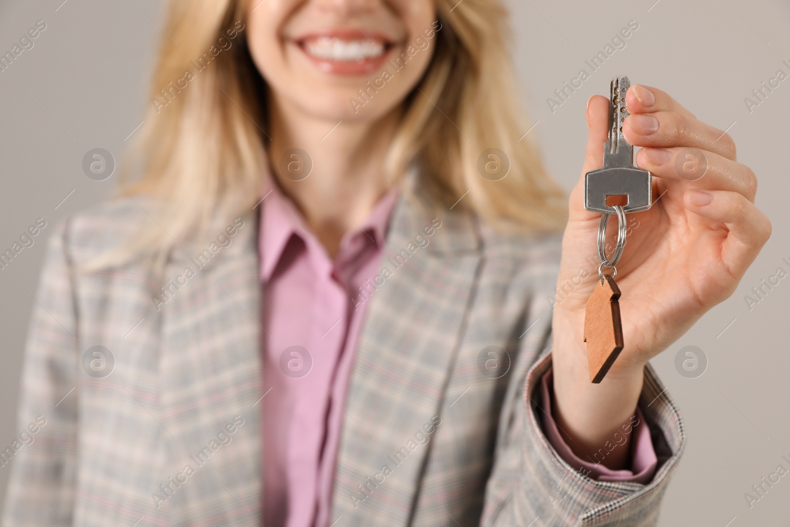 Real estate agent holding key against grey background, closeup Photo of Real estate agent holding key against grey background, closeup
