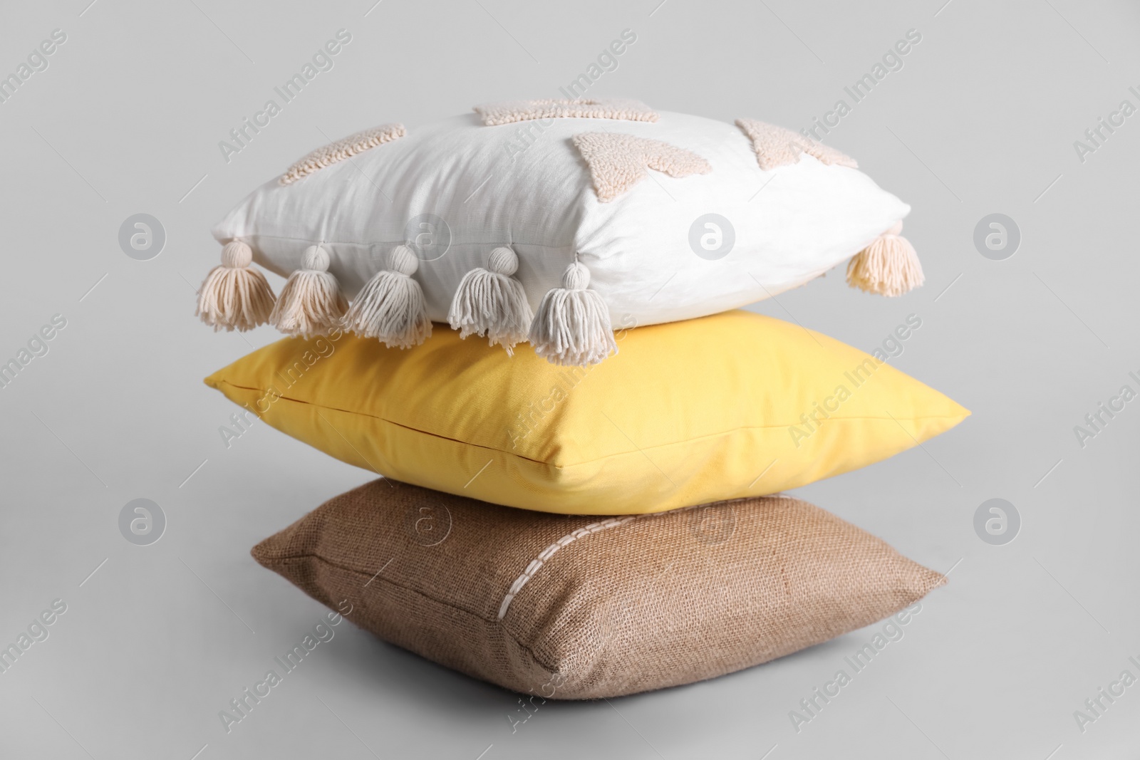 Stack of stylish soft pillows on grey background Photo of Stack of stylish soft pillows on grey background