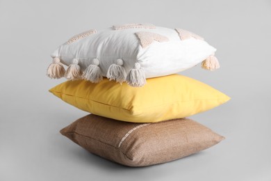 Stack of stylish soft pillows on grey background Photo of Stack of stylish soft pillows on grey background