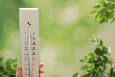 Woman with weather thermometer on blurred background, closeup. Space for text Photo of Woman with weather thermometer on blurred background, closeup. Space for text